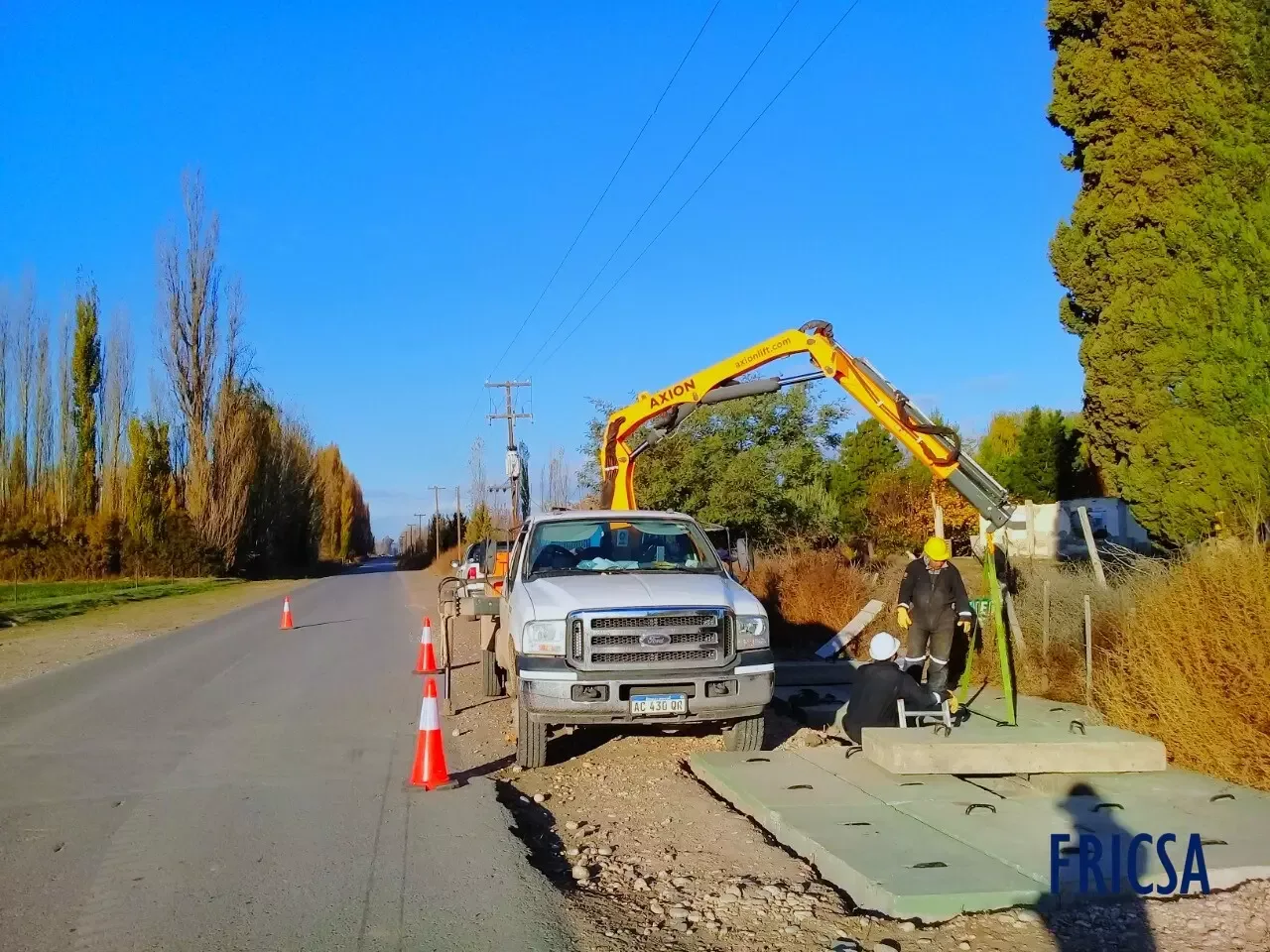 Camión con hidrogrúa trabajando junto a una cañería en campo